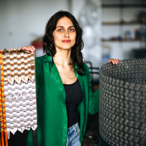 Alina Tenser wears a green shirt and stands with her sculptures in a studio at Lehigh University.