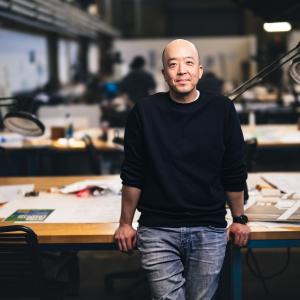 Eugene Han leaning on a table in his studio.