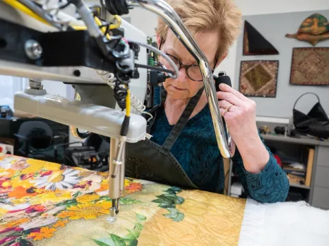 Profesor Anna Chupa making a quilt with petals and leaves.