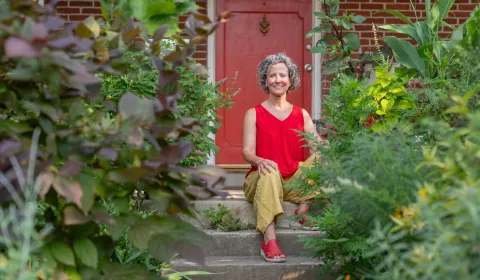 Deirdre Murphy sitting on steps in front of a red door.