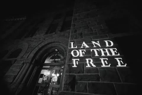 “Land of the Free” is projected onto the side of the Carbon County courthouse at night.