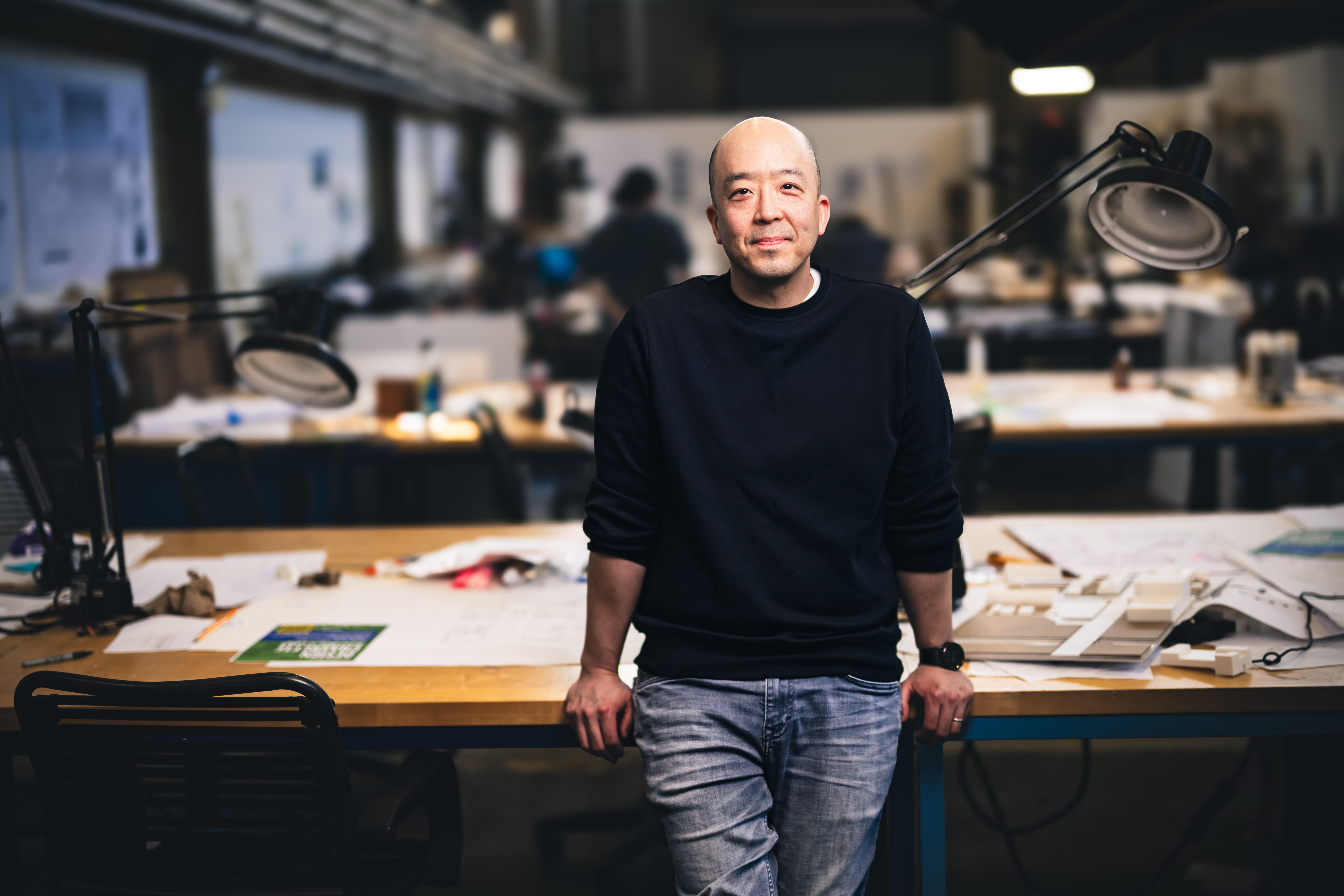 Eugene Han leaning on a table in his studio.