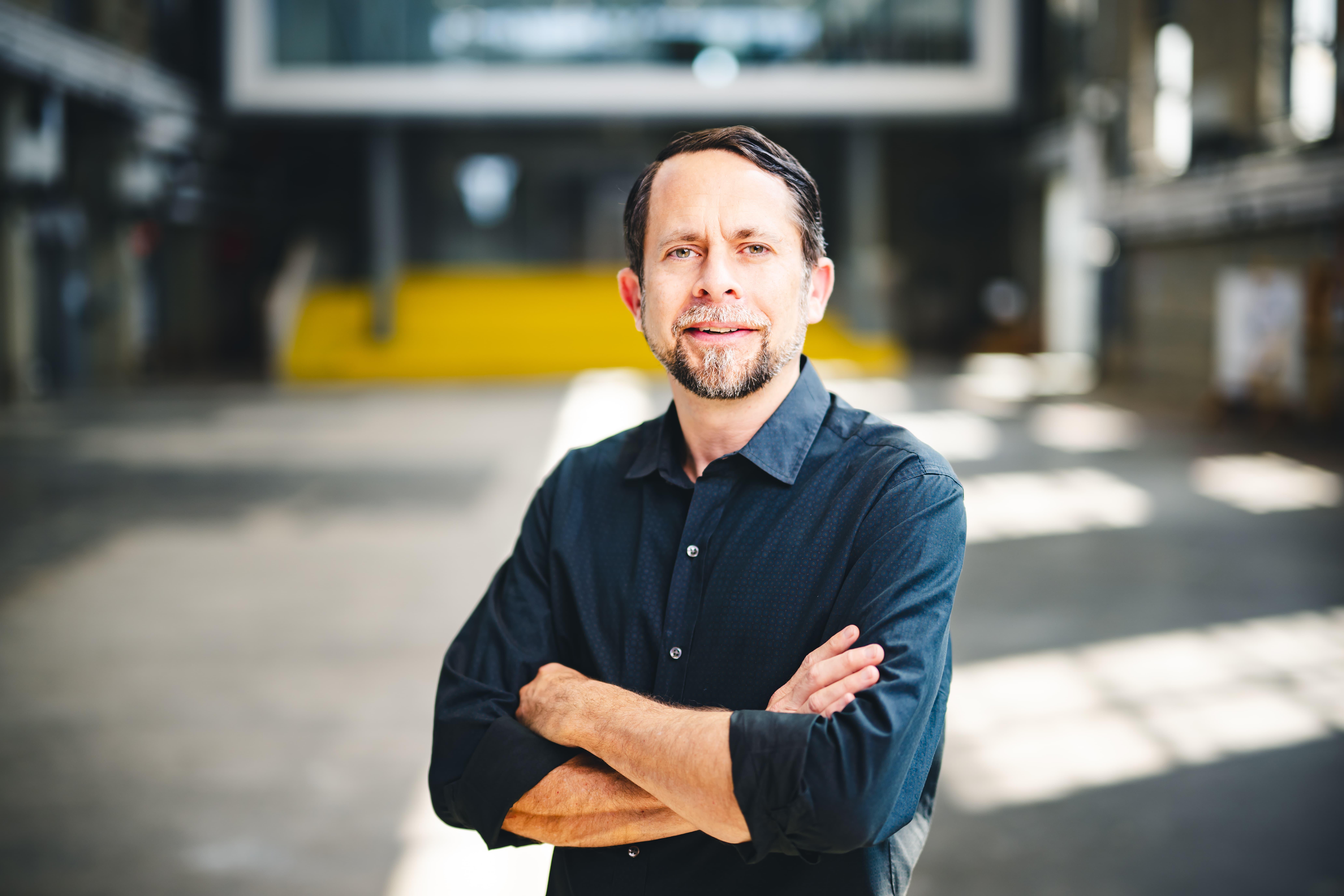 Nick Sawicki standing in a building with his arms folded.