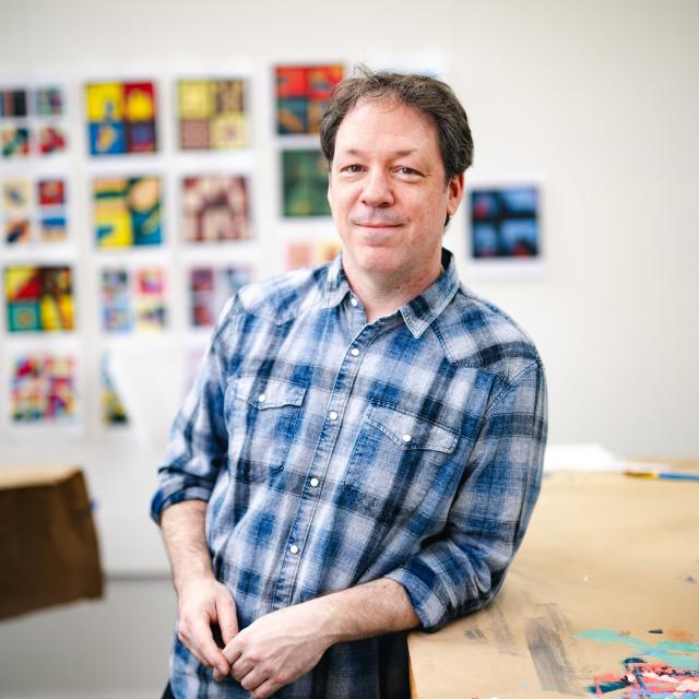 Jason Travers leaning on a table in his studio.