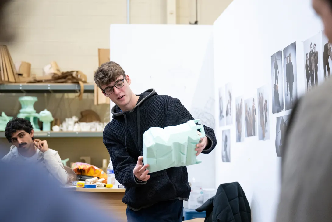Student showing foam prototype to other students