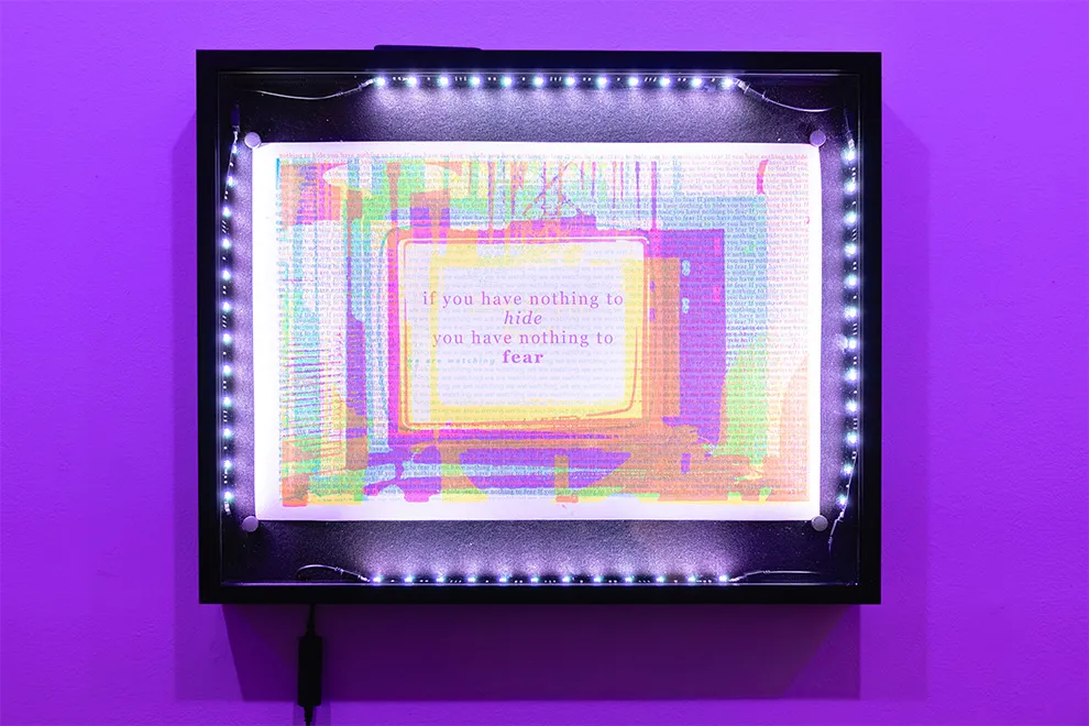 A risograph-inspired print in a black frame illuminated with RGB LED lights, featuring the image of a TV that appears to move closer as the lights change color.