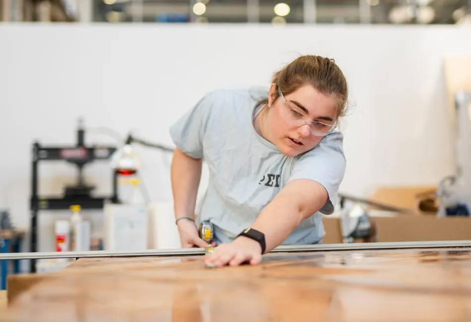 Annie Oatman '25 works on the top of a table that will be used in a private dining area inside the Lehigh Pub at the Clayton UC.