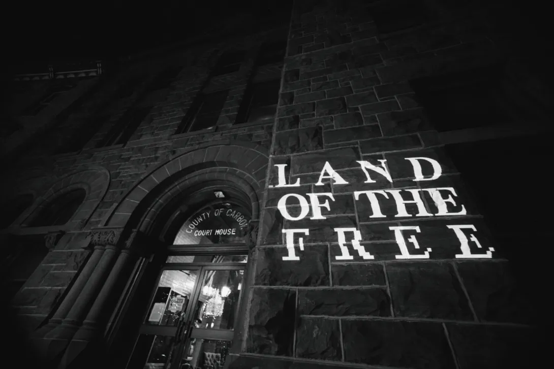 “Land of the Free” is projected onto the side of the Carbon County courthouse at night.