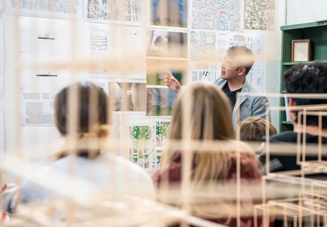 Professor speaking to his architecture students amid architectural models