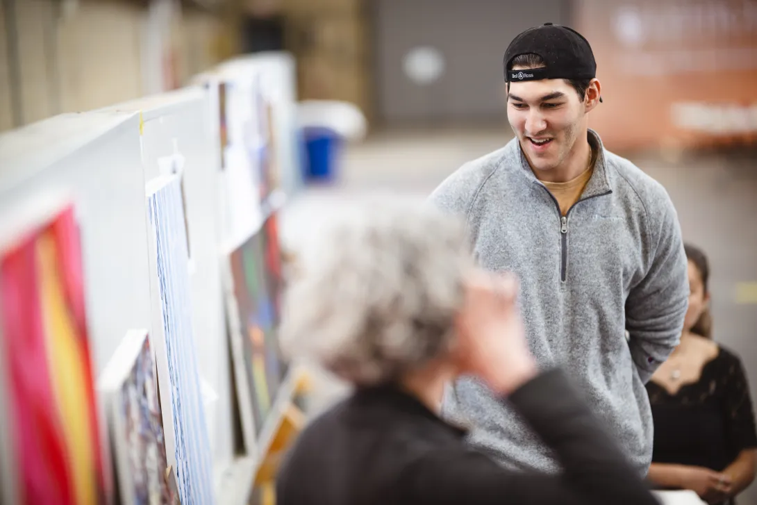 Student presenting his artwork to his professor